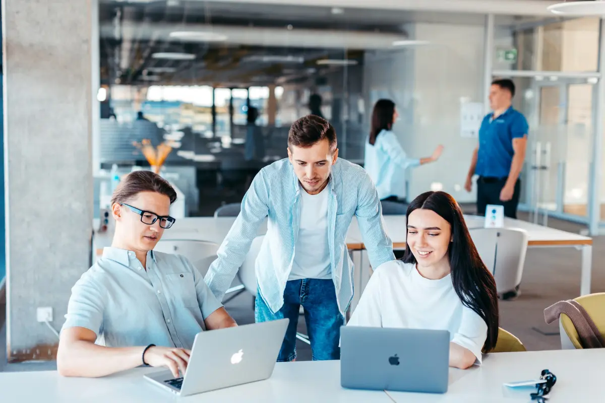 Team arbeitet gemeinsam am Laptop in einem hellen Büro